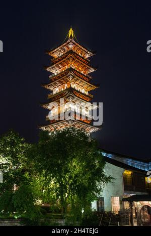 Die Weiße Lotus-Pagode oder Westpagode leuchtete nachts in der Wasserstadt Wuzhen, China, auf. Stockfoto