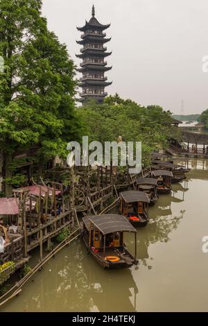 Die siebenstöckige White Lotus Pagode blickt auf traditionelle Holzboote im Kanal. Wuzhen, China. Stockfoto