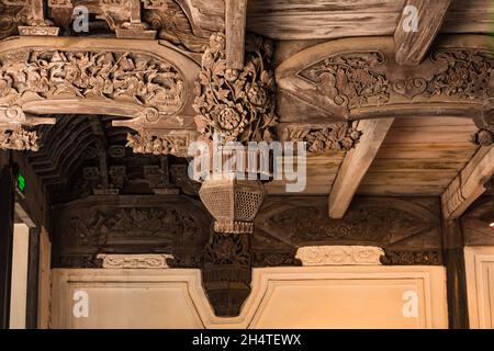 Kunstvolle Holzschnitzerei von Lotusblumen & eine Kampfszene an der Decke eines alten Gebäudes in Wuzhen, China. Stockfoto