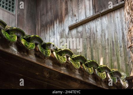 Aufwendige Entwürfe auf alten moosbedeckten Tonziegeln auf dem Dach eines alten Gebäudes in Wuzhen, China. Stockfoto