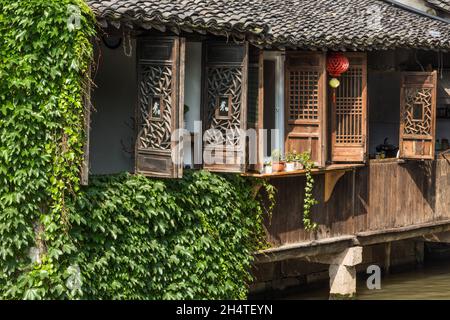 Hölzerne Gitterfenster auf traditionellen Wohnungen entlang des Kanals in der Wasserstadt Wuzhen, China. Stockfoto