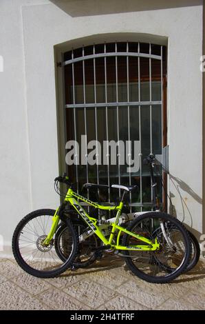 Ein gelbes Fahrrad ist in der Nähe des Tores eines weißen Hauses geparkt Stockfoto