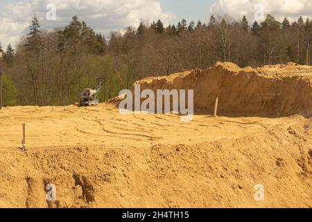 Sandplattform. Sand in die Basis legen. Viel Baumaterial. Bau einer Straßenkreuzung. Stockfoto