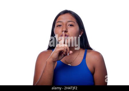 Shh, dunkelhäutige Frau, die um Stille bittet, isoliert auf weißem Hintergrund. Lateinische Frau mit indigener oder gemischter Ethnie. Dunkelhäutige Frau. Stockfoto