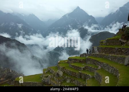 Touristen auf landwirtschaftlichen Terrassen und nebligen Bergen, Machu Picchu (Weltkulturerbe), Sacred Valley, Peru, Südamerika Stockfoto