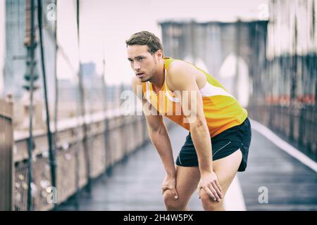 Müder Läufer, der beim Jogging-Training auf der Brooklyn Bridge in New York City, NYC, eine Atempause einnimmt, aktiv, gesund und gesund. Mann beim Laufen Stockfoto