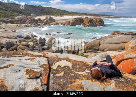 Frau, die auf Felsen am Beerfass Beach liegt Stockfoto