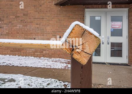 Mit Schnee bedeckte Zaunpfosten vor dem Eingang des Gebäudes Stockfoto