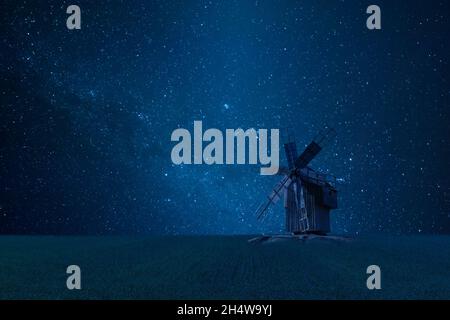 Nachtlandschaft mit alter Windmühle im Feld, helle Sterne am Himmel, endlose Galaxie Stockfoto