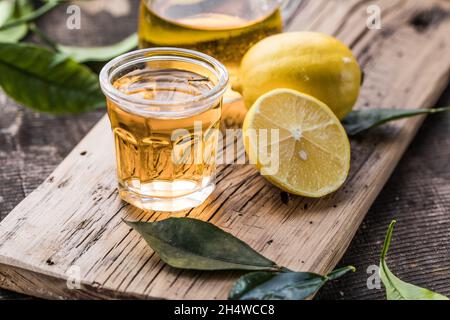 Traditioneller hausgemachter Zitronenlikör Limoncello und frische Zitrusfrüchte auf einem Holztisch. Stockfoto