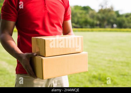 Liefermann in roter Uniform mit Paketkarton Stockfoto