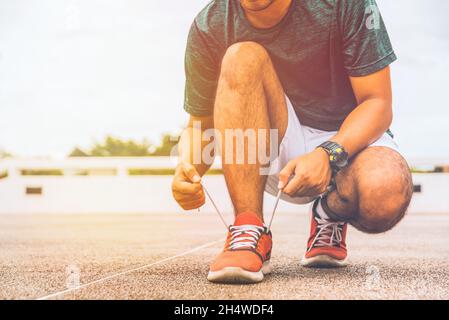 Läufer junger Mann binden Schnürsenkel immer bereit für das Rennen auf Laufstrecke. Stockfoto