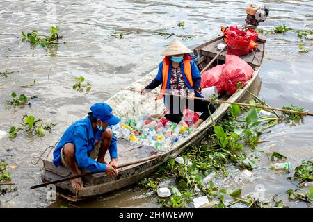 Arme Arbeiter nehmen Plastikflaschen auf, die die Umwelt am Fluss in Vietnam verschmutzen Stockfoto