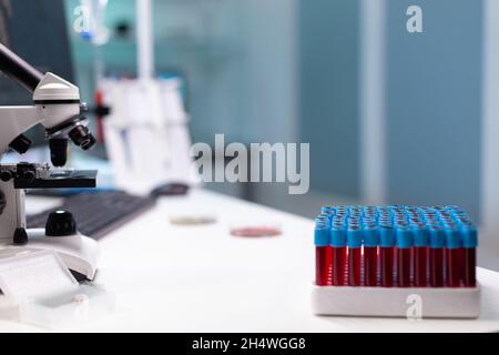 Nahaufnahme des Labortisches mit professionellen Forschungsgeräten. Tablett mit Vakuumier mit Blut für mikroskopische Untersuchungen, Mikropipette und Mikroskop. Werkzeuge für die wissenschaftliche Entwicklung Stockfoto
