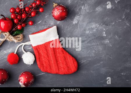 Roter Weihnachtsstiefel-Strumpf der Weihnachtsmann in der Nähe von Weihnachtsdekorationen auf blauem Beton-Hintergrund. Abstrakter Weihnachtshintergrund. Speicherplatz kopieren Stockfoto