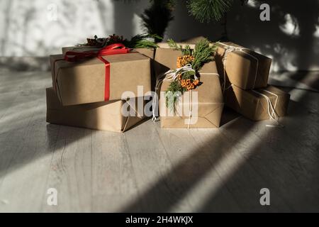 Geschenkboxen im Zimmer zu Hause auf dem Boden unter dem Baum. Bastelverpackung. Heiligabend. Dekoration von hausgemachten Überraschungen für die Familie. Stockfoto