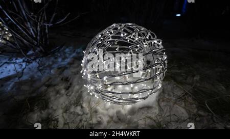 Weihnachtslichter in Form eines Balls auf dem Schnee. Stockfoto