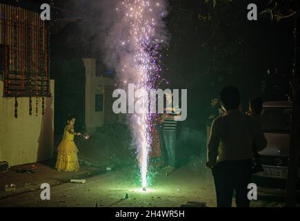 Ghaziabad, Indien. November 2021. Indische Familie spielt mit einem Brunnenfeuerwerk während der Diwali-Festfeier in Ghaziabad. Indische Staaten und Gewerkschaftsgebiete haben Richtlinien erlassen, die die Verwendung von Feuerwerkskörpern gemäß den Anordnungen des Obersten Gerichtshofs einschränken, aber immer noch wurde mit einem Verbot von Feuerwerkskörpern gefeiert. Kredit: SOPA Images Limited/Alamy Live Nachrichten Stockfoto