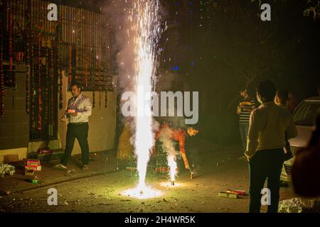 Ghaziabad, Indien. November 2021. Indische Familie spielt mit einem Brunnenfeuerwerk während der Diwali-Festfeier in Ghaziabad. Indische Staaten und Gewerkschaftsgebiete haben Richtlinien erlassen, die die Verwendung von Feuerwerkskörpern gemäß den Anordnungen des Obersten Gerichtshofs einschränken, aber immer noch wurde mit einem Verbot von Feuerwerkskörpern gefeiert. Kredit: SOPA Images Limited/Alamy Live Nachrichten Stockfoto