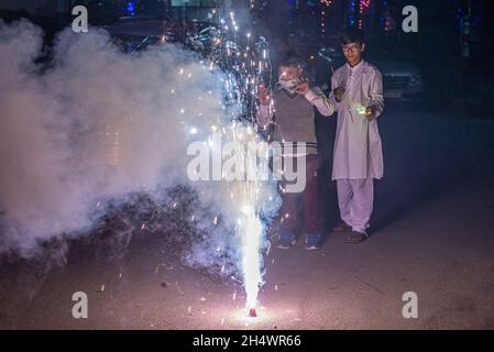 Ghaziabad, Indien. November 2021. Indische Jungen spielen während der Diwali-Feier in Ghaziabad mit einem Brunnenfeuerwerk.Indische Staaten und Gewerkschaftsgebiete haben Richtlinien erlassen, die die Verwendung von Feuerwerkskörpern gemäß den Befehlen des Obersten Gerichtshofs einschränken, aber die Menschen feierten immer noch mit einem Feuerwerkskörper-Verbot. Kredit: SOPA Images Limited/Alamy Live Nachrichten Stockfoto