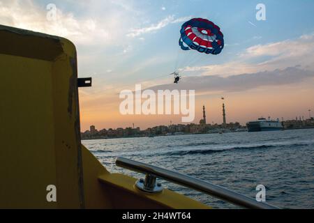 Non Exclusive: HURGHADA, ÄGYPTEN - 31. OKTOBER 2021 - Ein Parasailer ist gegen die Skyline von Hurghada, Ägypten, abgebildet. Stockfoto