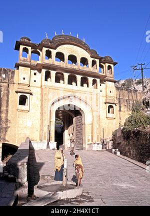 Frau und Kind stehen vor dem Eingang zum Samode Palace, Samode, Rajasthan, Indien, an einem Trinkbrunnen. Stockfoto