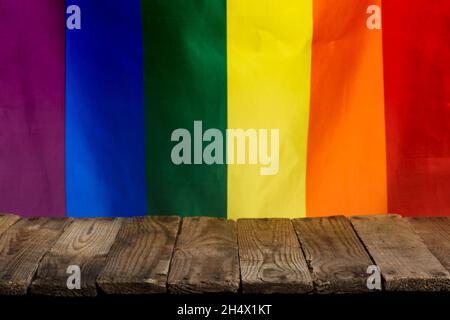 Leerer rustikaler Holztisch aus alten Brettern mit Stolz Regenbogenfahne auf dem Hintergrund. Stockfoto