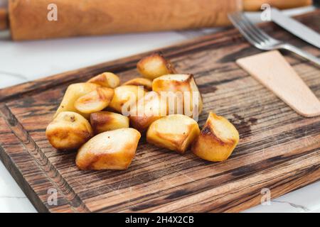 Geröstete Kartoffeln auf einem Holzbrett auf einer Küchenarbeitsplatine Stockfoto