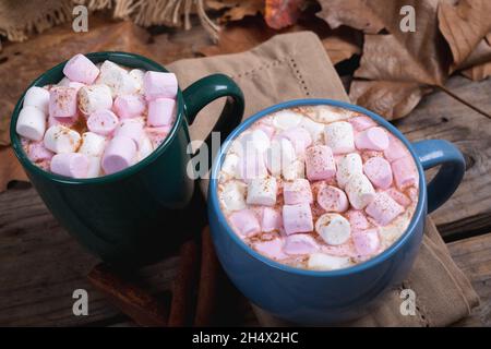 Rosafarbene und weiße Marshallows mit heißem Schokoladengetränk, gefüllt in Tassen auf dem Tisch im Café Stockfoto