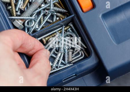 Eine Schraube von Hand aus dem Werkzeugkasten aufnehmen Stockfoto