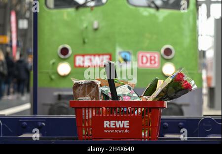 05. November 2021, Hessen, Frankfurt/Main: ILLUSTRATION - Ein gefüllter Einkaufskorb steht vor der Lokomotive bei der Präsentation des temporären Projekts 'Fair Supermarket in the Train' im Frankfurter Hauptbahnhof. Der FAIR Supermarktzug ist ein voll funktionaler Supermarkt mit Fairtrade, Bio- und Regionalkost in einem umgebauten Zug. Partner sind Fairtrade, DB Regio und Rewe Region Mitte. Nach dem Start am 5. November 2021 wird der Zug durch sechs hessische Städte fahren. Foto: Arne Dedert/dpa Stockfoto