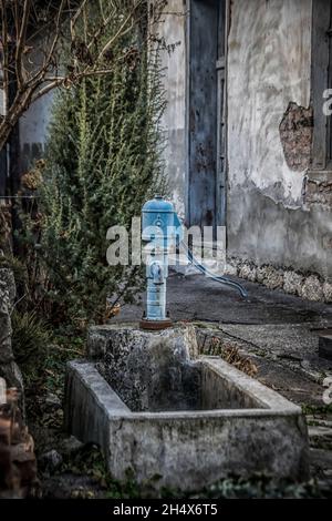 Blauer Vintage Wasserhahn in einem ländlichen Hof Stockfoto