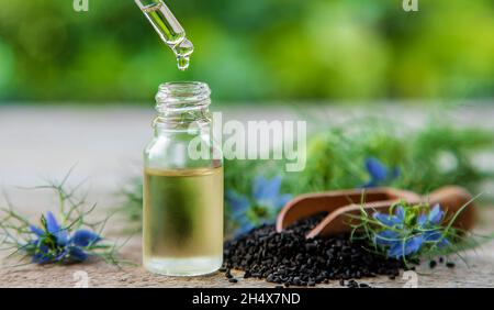 Schwarzes Kreuzkümmelöl in einer Flasche. Selektiver Fokus. Natur. Stockfoto