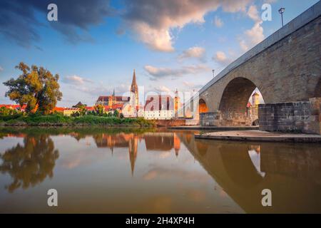 Regensburg, Deutschland. Stadtbild von Regensburg, Deutschland mit der alten Steinbrücke über die Donau und dem Petersdom bei Sonnenuntergang im Sommer. Stockfoto