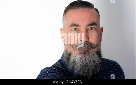 Nahaufnahme eines Mannes im Hipster-Stil, eines großen grauen Bartes und honigfarbener Augen Stockfoto