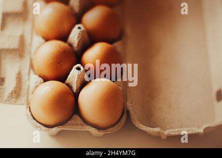 Frische braune Hühnereier liegen in einem Pappkarton, der in einem Lebensmittelgeschäft gekauft wurde und von Sonnenlicht beleuchtet wird. Gesundes Frühstück. Eiweißfutter. Stockfoto