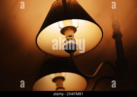 Ein wunderschöner, eleganter Kronleuchter mit hell leuchtenden Lampen hängt im Motel und sorgt nachts für warmes Licht und Komfort. Innen. Stockfoto