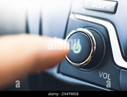 Der Fahrer drückt im Fahrzeug den ein-/aus-Schalter des Audioplayers Stockfoto