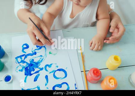 Mutter und Tochter zusammen zu Hause mit Pinsel und Wasserfarben malen Stockfoto