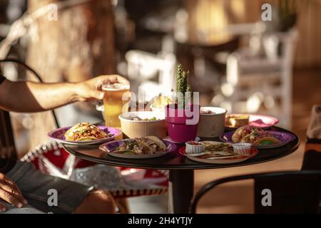 Serviert wird ein traditioneller mexikanischer Tisch. Outdoor Food Konzept . Eine nicht erkennbare Gruppe von Freunden, die in einem Restaurant mexikanisches Essen aßen. Stockfoto