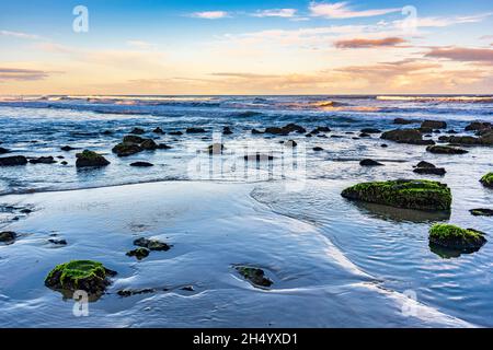 Ruhiger und einsamer Strand mit Felsen bei Sonnenuntergang in der Stadt Torres in Rio Grande do Sul Stockfoto