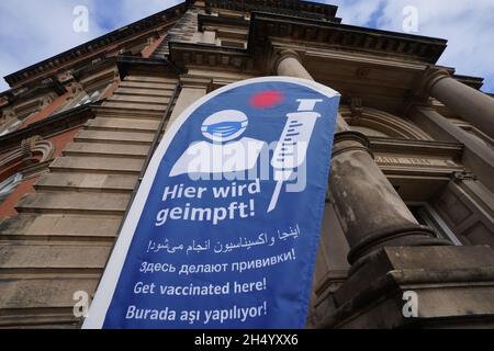 Hamburg, Deutschland. November 2021. „Hier impfen!“ Liest ein Banner vor der Staats- und Universitätsbibliothek Hamburg. Laut einem Sprecher der Gesundheitsbehörde sei bei dem offenen Impfangebot genügend Corona-Impfstoff auf Lager, um allen zu dienen. (To dpa 'offenes Impfangebot in der Universitätsbibliothek - lange Schlange vor der Tür') Quelle: Marcus Brandt/dpa/Alamy Live News Stockfoto