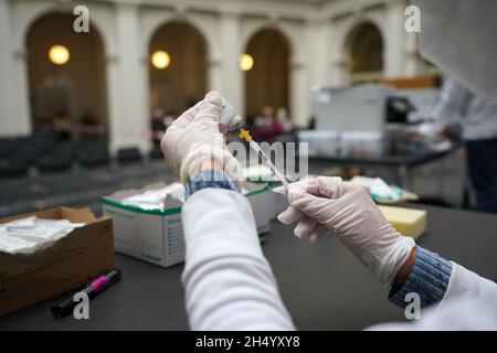 Hamburg, Deutschland. November 2021. Ein Mitglied des Mobile Immunization Teams erstellt in der Staats- und Universitätsbibliothek Hamburg eine Impfstoffspritze. Ein Sprecher der Gesundheitsbehörde sagte, dass beim offenen Impfangebot genügend Corona-Impfstoff auf Lager war, um allen zu dienen. (To dpa 'offenes Impfangebot in der Universitätsbibliothek - lange Schlange vor der Tür') Quelle: Marcus Brandt/dpa/Alamy Live News Stockfoto