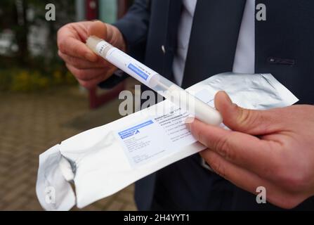 05. November 2021, Hessen, Büdingen: Polizeipressereferent Tobias Kremp steht heute Nachmittag mit einem Reagenzglas vor der Wolfgang-Konrad-Halle im Kreis Lorbach. Bei der Suche nach der Mutter eines 1999 gefundenen toten Säuglings wird hier ab Samstag (06.11.2021) eine DNA-Serienuntersuchung stattfinden. Die Ermittler hoffen, Fortschritte bei der Lösung des mutmaßlichen Mordes zu erzielen. Rund 600 Frauen aus der Umgebung der Stadt im Bezirk Wetterau, die zwischen 13 und 30 Jahre alt waren, als die Leiche gefunden wurde, wurden gebeten, freiwillig eine Speichelprobe zu geben. Foto: Frank Rumpenhorst/dpa Stockfoto