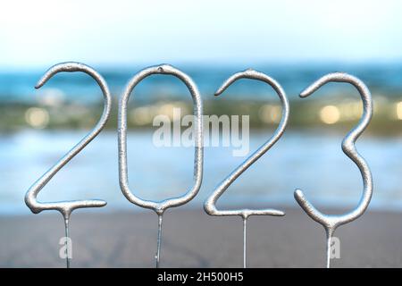 Die Zahlen für das kommende neue Jahr 2023 inmitten von Wellen am Strand. Das Konzept der Feierlichkeiten zum neuen Jahr in einem exotischen Land. Nahaufnahme Stockfoto