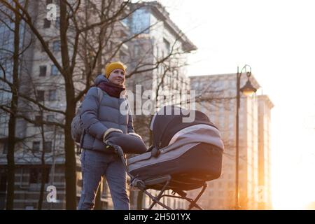 Glückliche junge Mutter mit Kinderwagen während des Spaziergangs Stockfoto