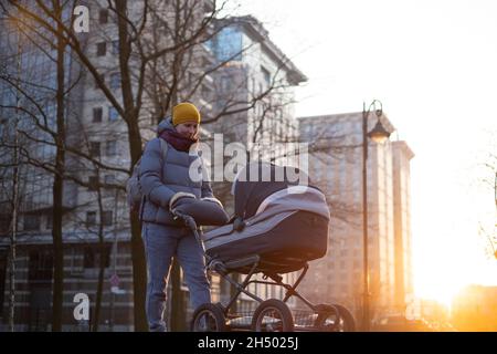 Glückliche junge Mutter mit Kinderwagen während des Spaziergangs Stockfoto