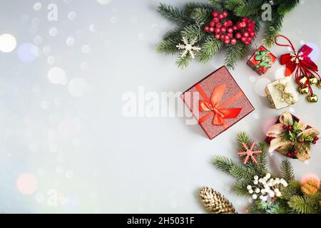 Rahmen aus Zweigen weihnachtsbaum, braunen natürlichen Kiefernzapfen und roten Beeren auf Schnee mit Platz für Text. Draufsicht, flach liegend Stockfoto