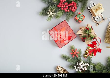 Rahmen aus Zweigen weihnachtsbaum, braunen natürlichen Kiefernzapfen und roten Beeren auf Schnee mit Platz für Text. Draufsicht, flach liegend Stockfoto