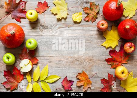 Herbstrand aus Äpfeln, Kürbis und abgefallenen Blättern auf altem Holztisch. Thanksgiving-Tageskonzept Thanksgiving Kürbis mit Früchten. Obst und Gemüse Stockfoto